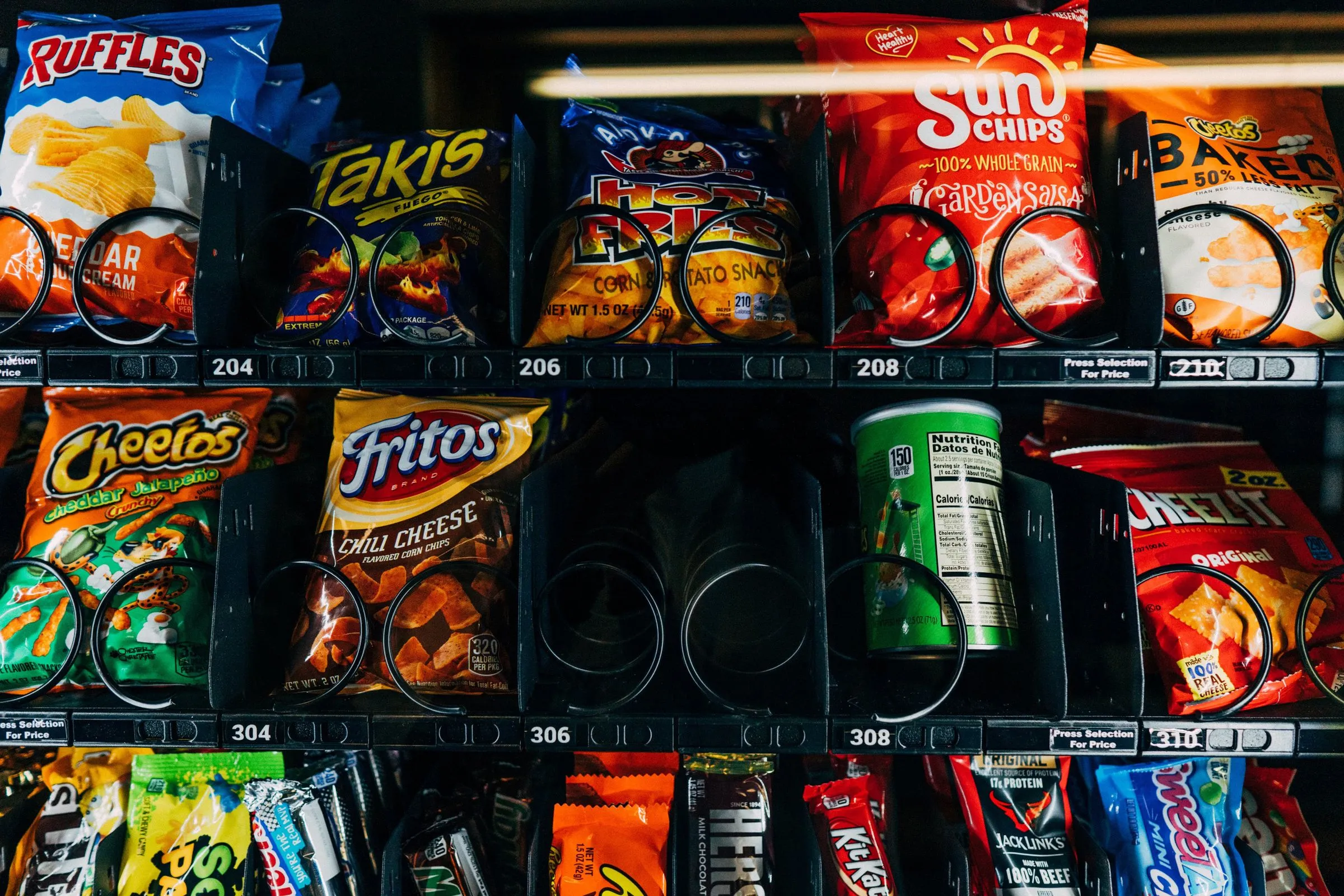 Bags of chips and chocolate bars on the shelves of a stocked vending machine. Illustrative photo.